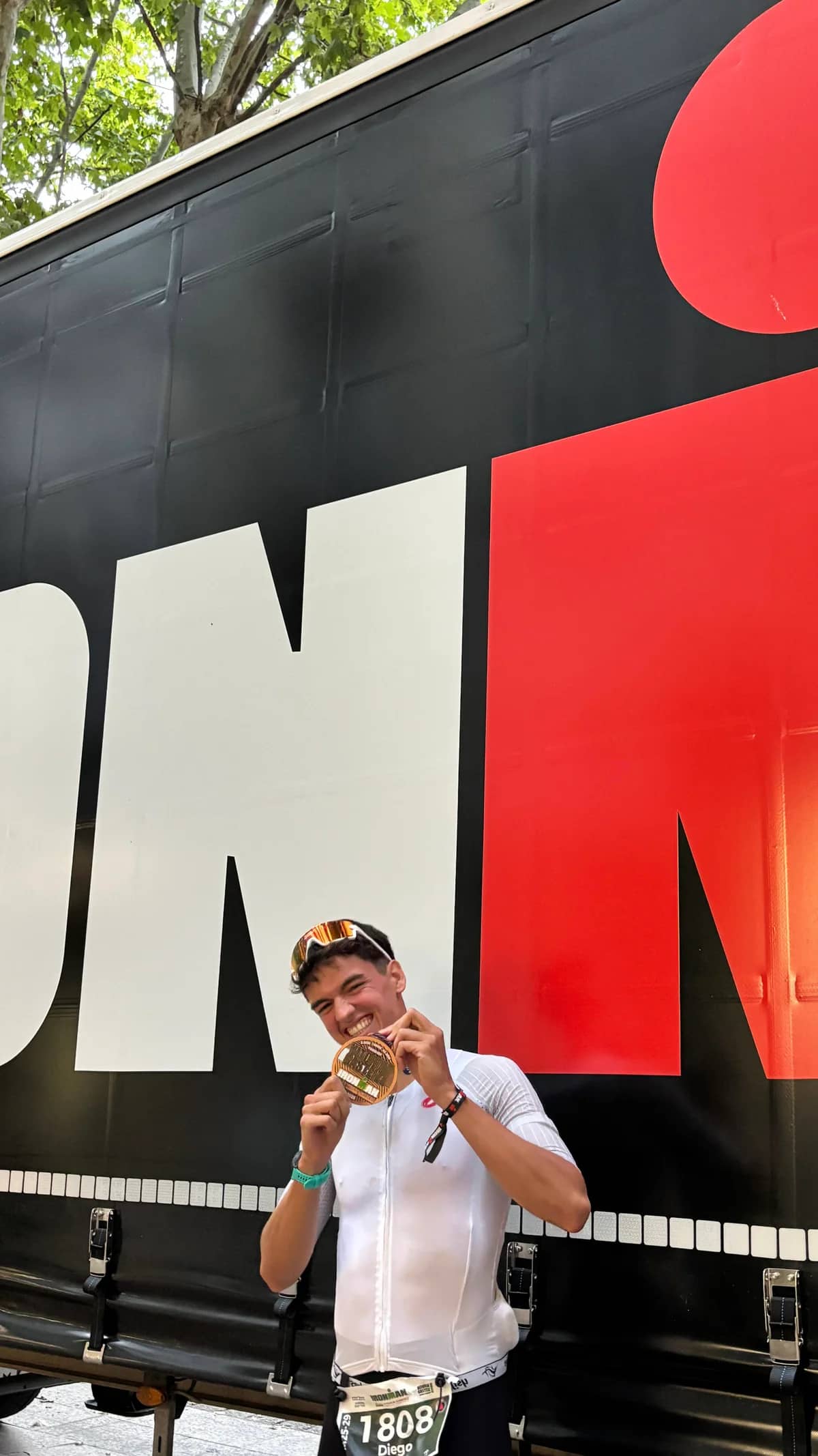 Diego Martí sonríe mientras muestra su medalla después de completar un Ironman.